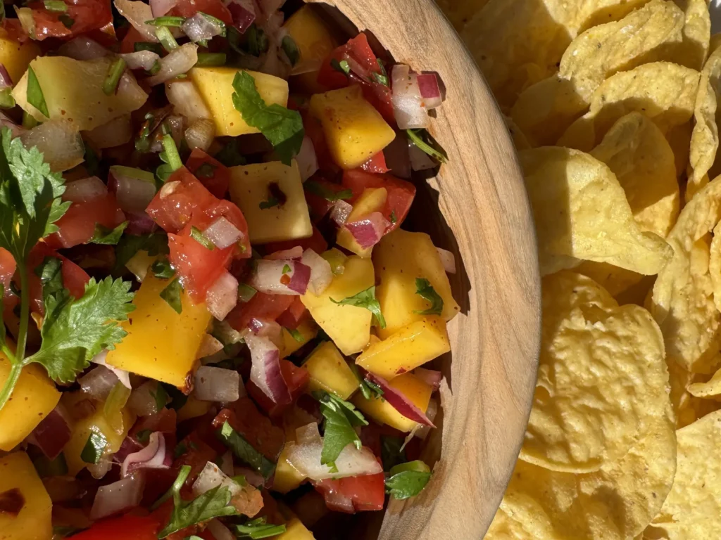 Finished product of Fresh Mango Salsa in a bowl with round tortilla chips for dipping.