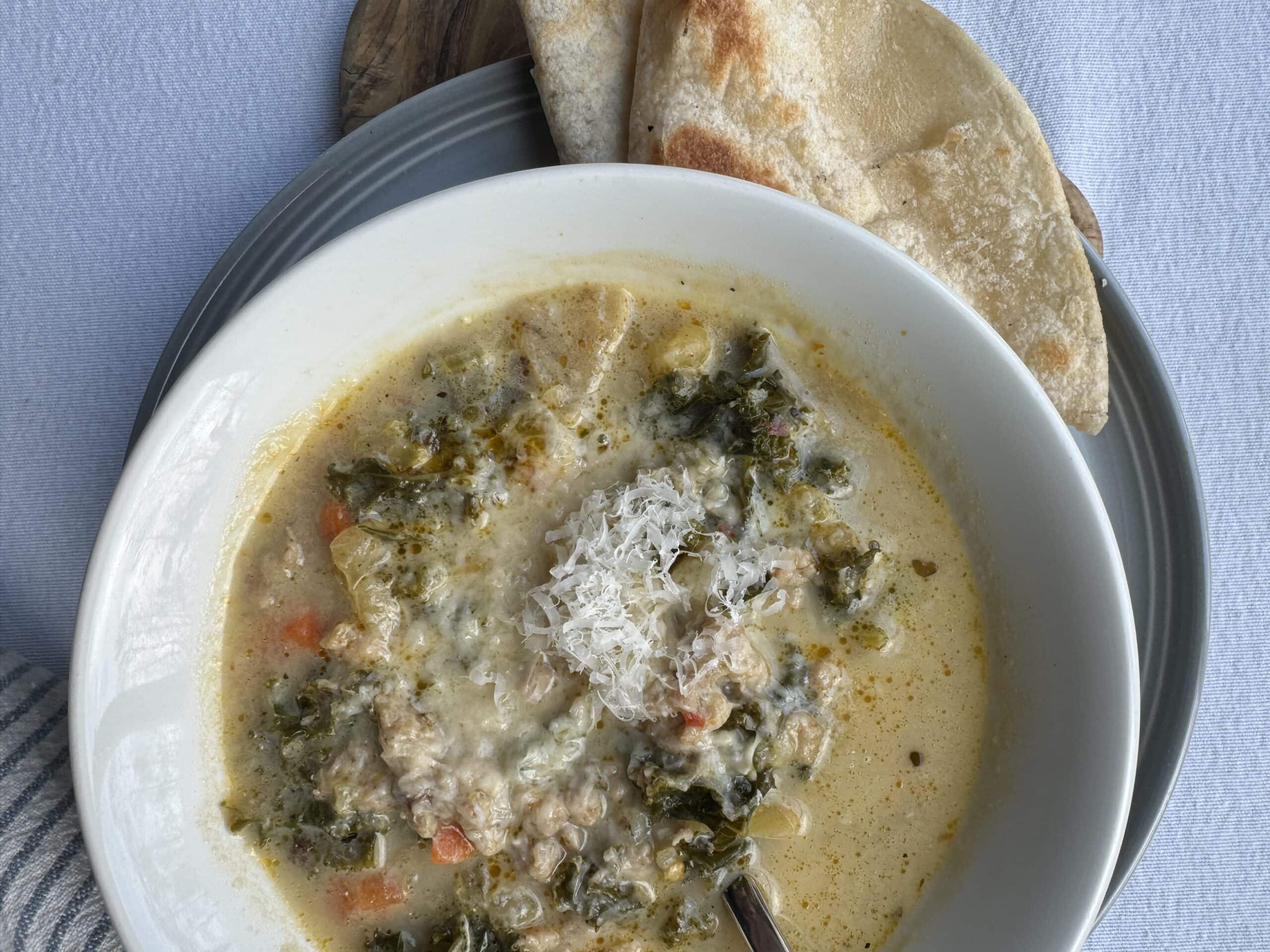 Creamy parmesan sausage soup in a bowl, served with flatbread.