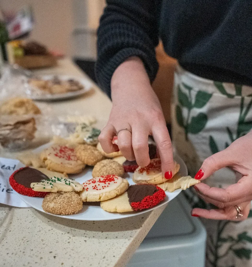 Image of the baker's hands gently placing a variety of cookies, made from the same Vanilla Sugar Cookie dough, onto a platter.