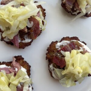 Overhead image of finished product: potato latkes with corned beef and cabbage, on white platter.
