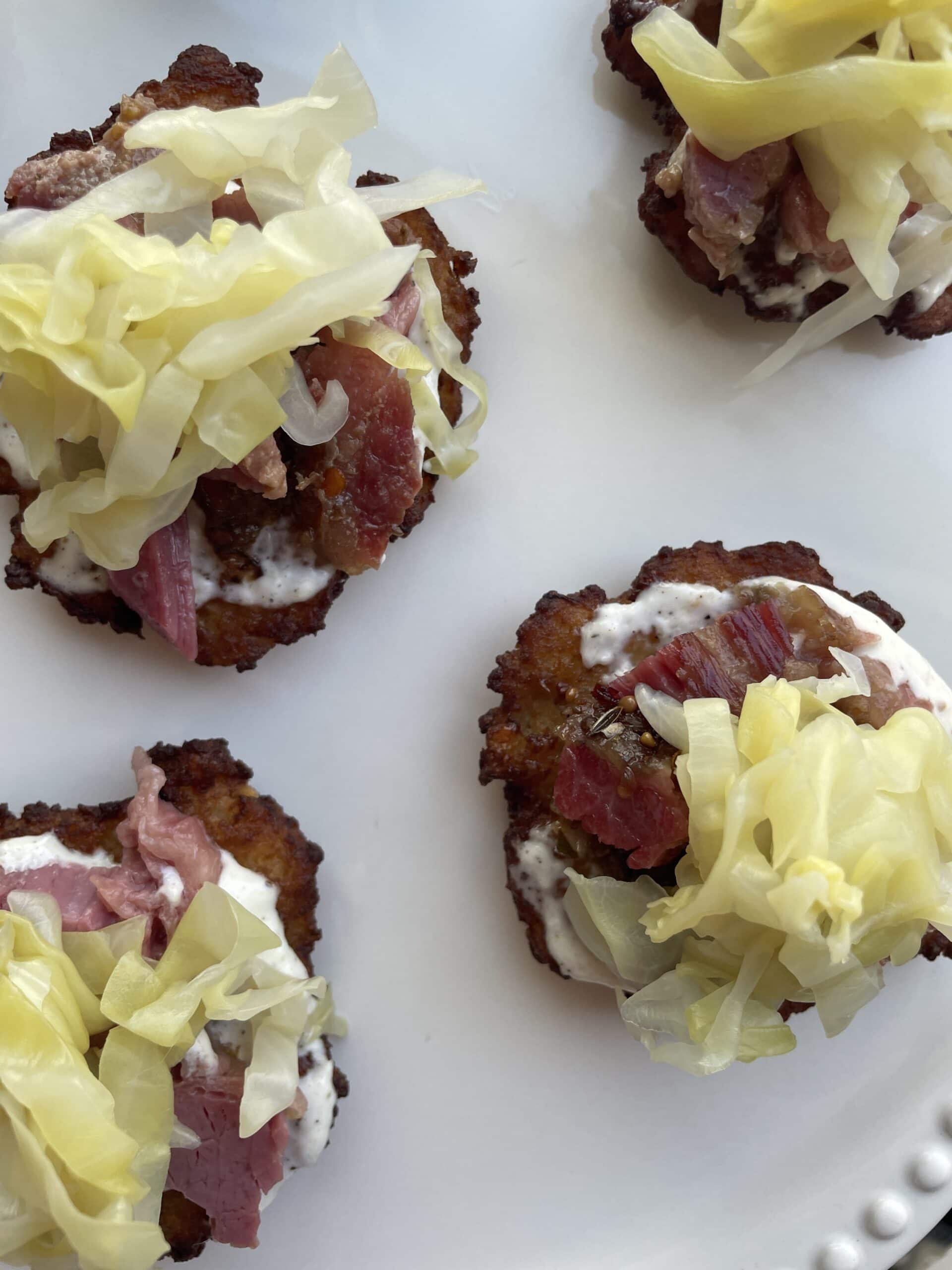 Overhead image of finished product: potato latkes with corned beef and cabbage, on white platter.