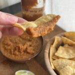 Salsa with a bowl of tortilla chips and lime wedges.