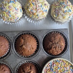 Overhead shot of Carrot and Banana Muffins. Some with frosting and sprinkles, some bare.