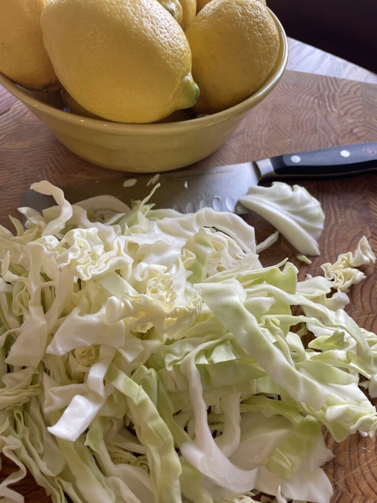 Freshly cut green cabbage, ready to be quick-pickled. Lemons in the background.
