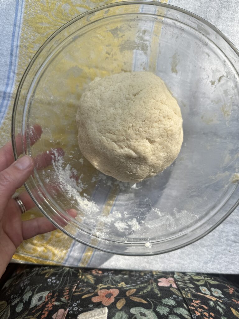 Three stages of the dough coming together: pouring the cream into the dry ingredients, combining the wet and dry ingredients, the dough fully formed once it has come together.