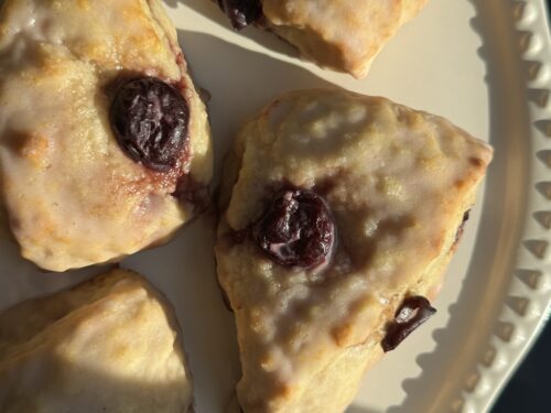 Overhead photo of finished product: Cherry Almond Scones with a light glaze, plated on a cake stand.