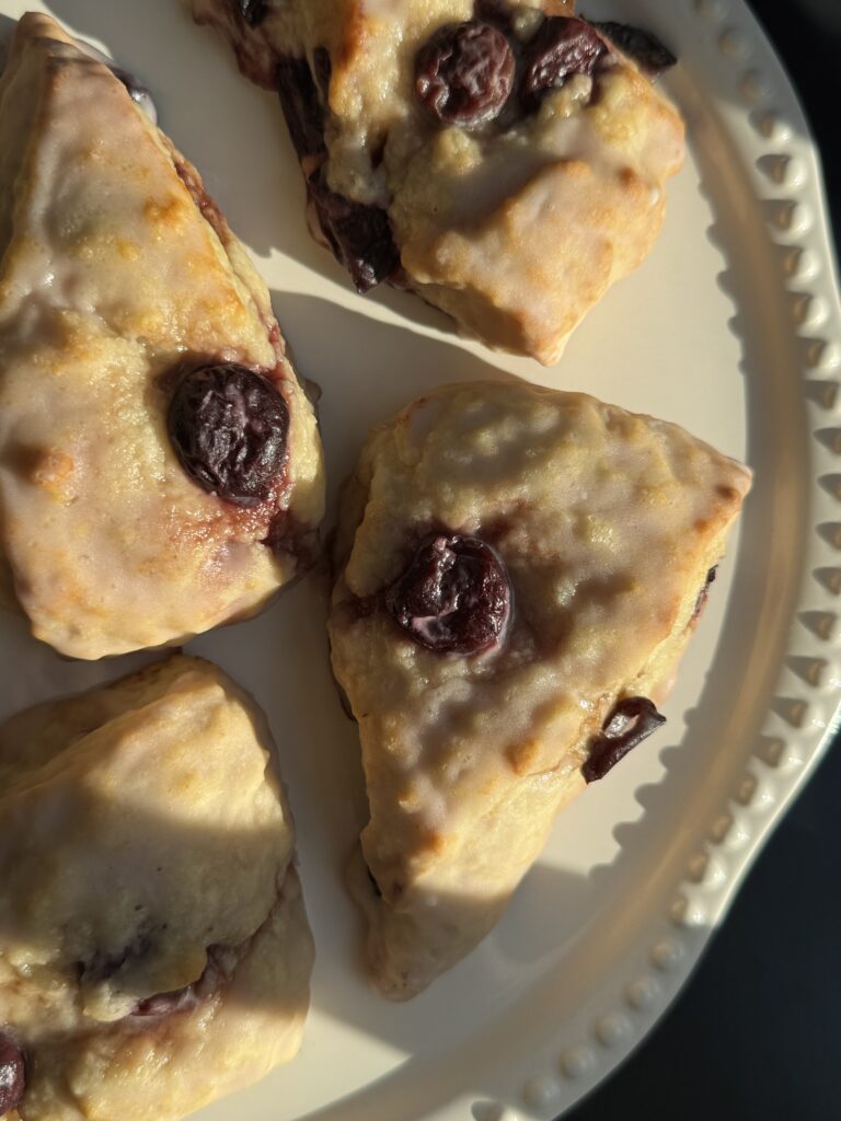 Overhead photo of finished product: Cherry Almond Scones with a light glaze, plated on a cake stand.