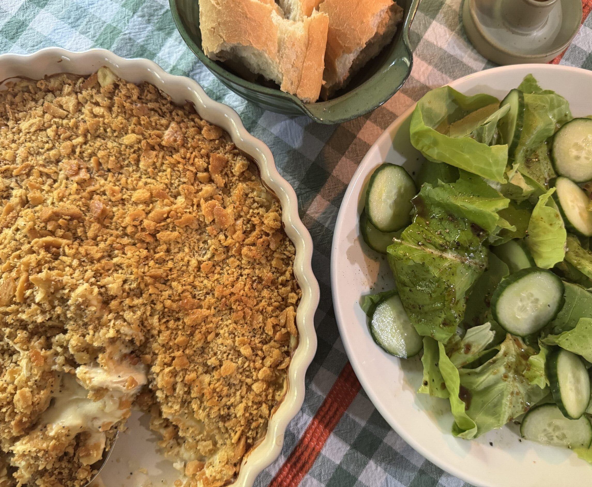 Table setting with Chicken Poppyseed, side salad of romaine and cucumbers, and crusty sourdough bread.