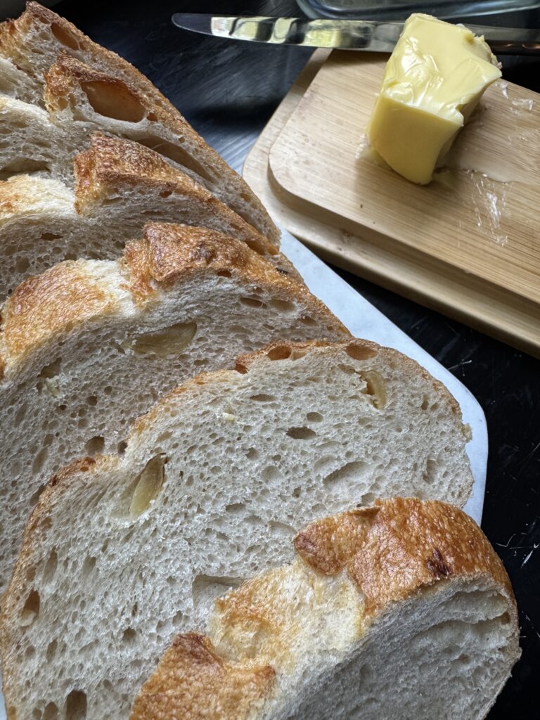 Fresh, sliced sourdough bread, ready to be slathered in butter and toasted in the skillet.