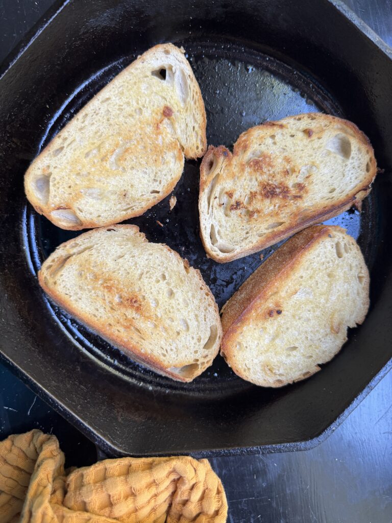 Toasted sourdough slices in a cast iron skillet.