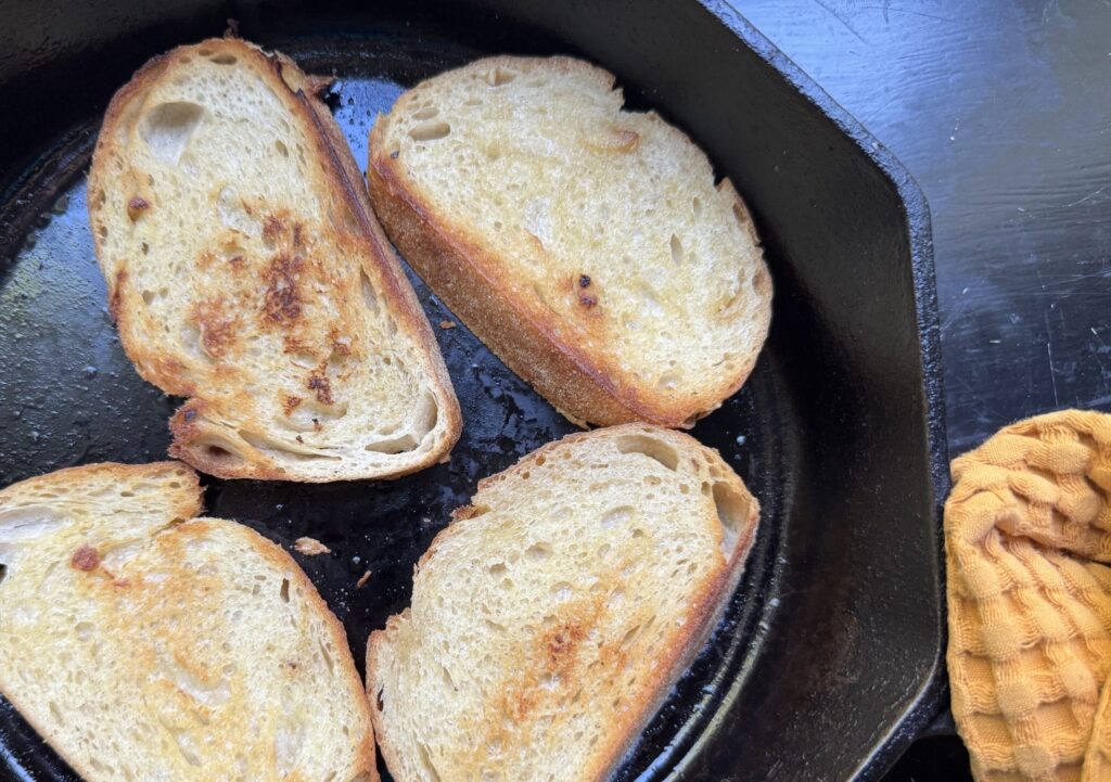 Toasted sourdough slices in a cast iron skillet.