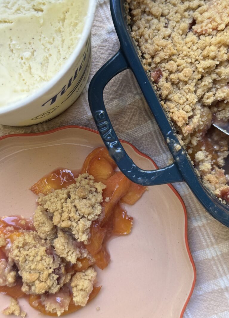 Plated Nectarine Crumble next to a carton of vanilla ice cream.