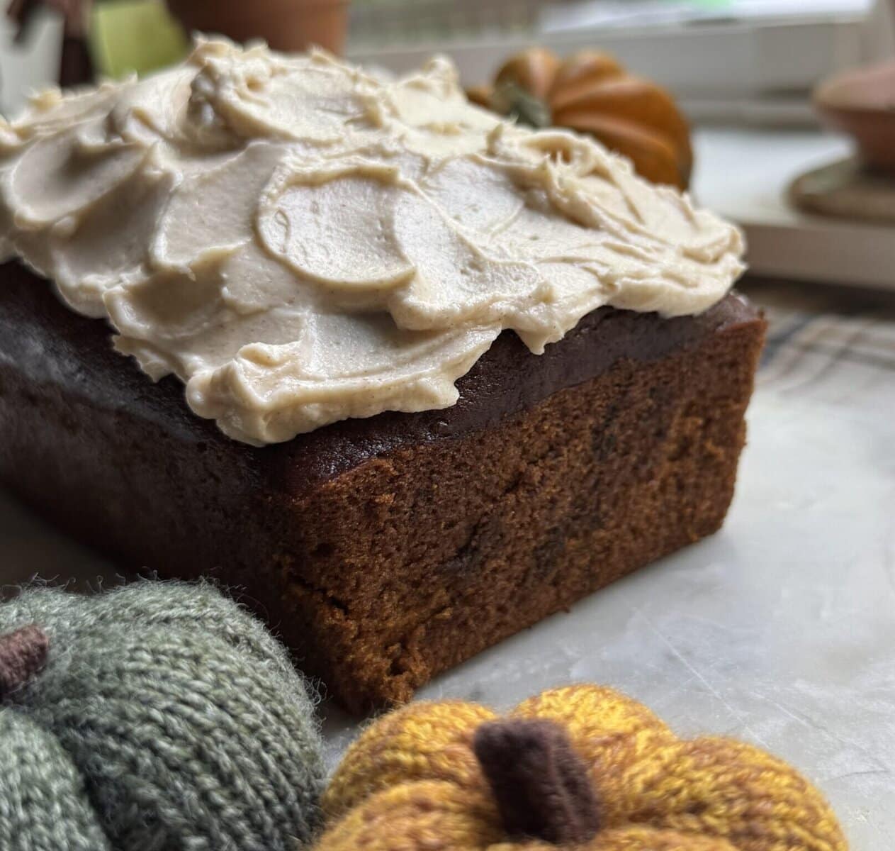 Small decorative pumpkins and a finished pumpkin bread with frosting.