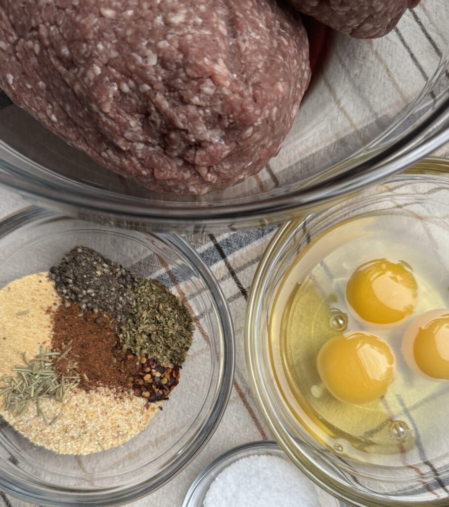 Fresh ingredients of lean ground beef, eggs, breadcrumbs, and spices.