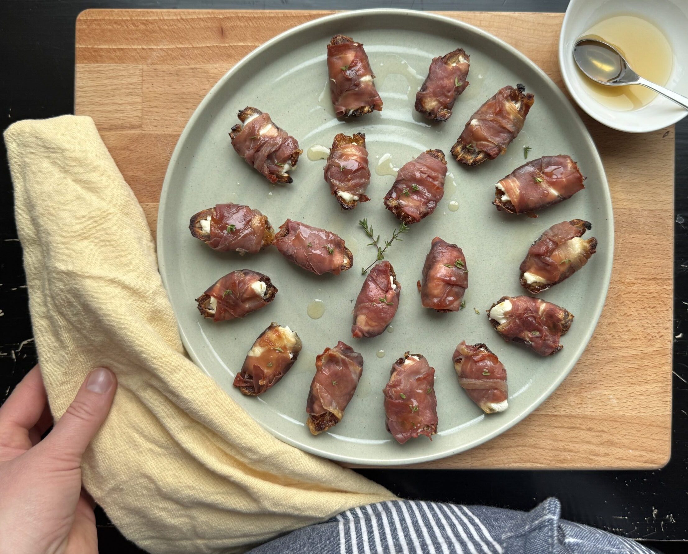 Dates wrapped in prosciutto with honey on the side for glazing.