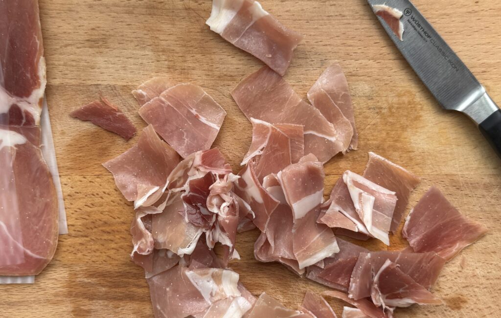 Prosciutto pieces on a cutting board.