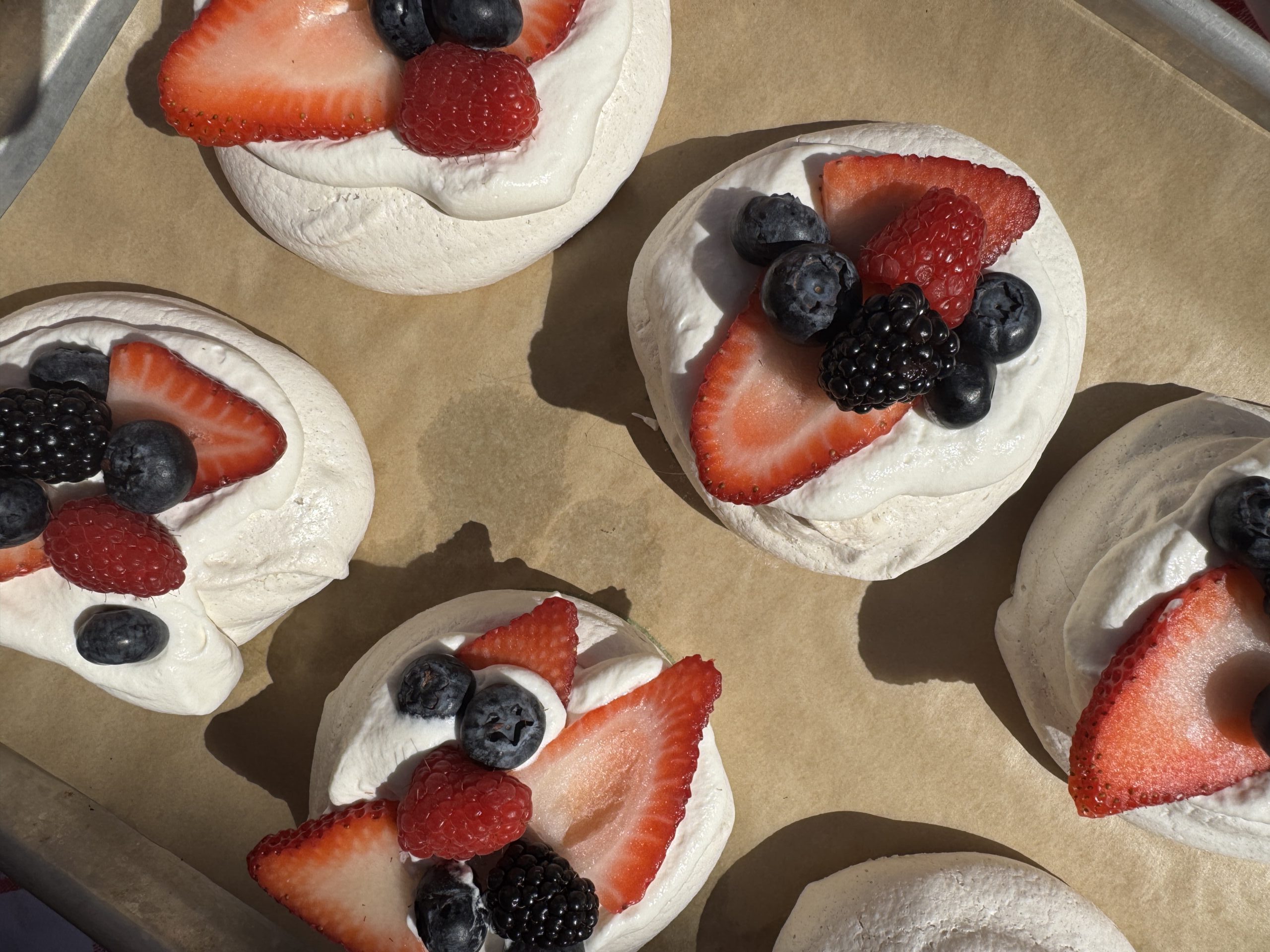 Mini Pavlova Nests with Vanilla Bean Whipped Cream, and an assortment of fresh berries.