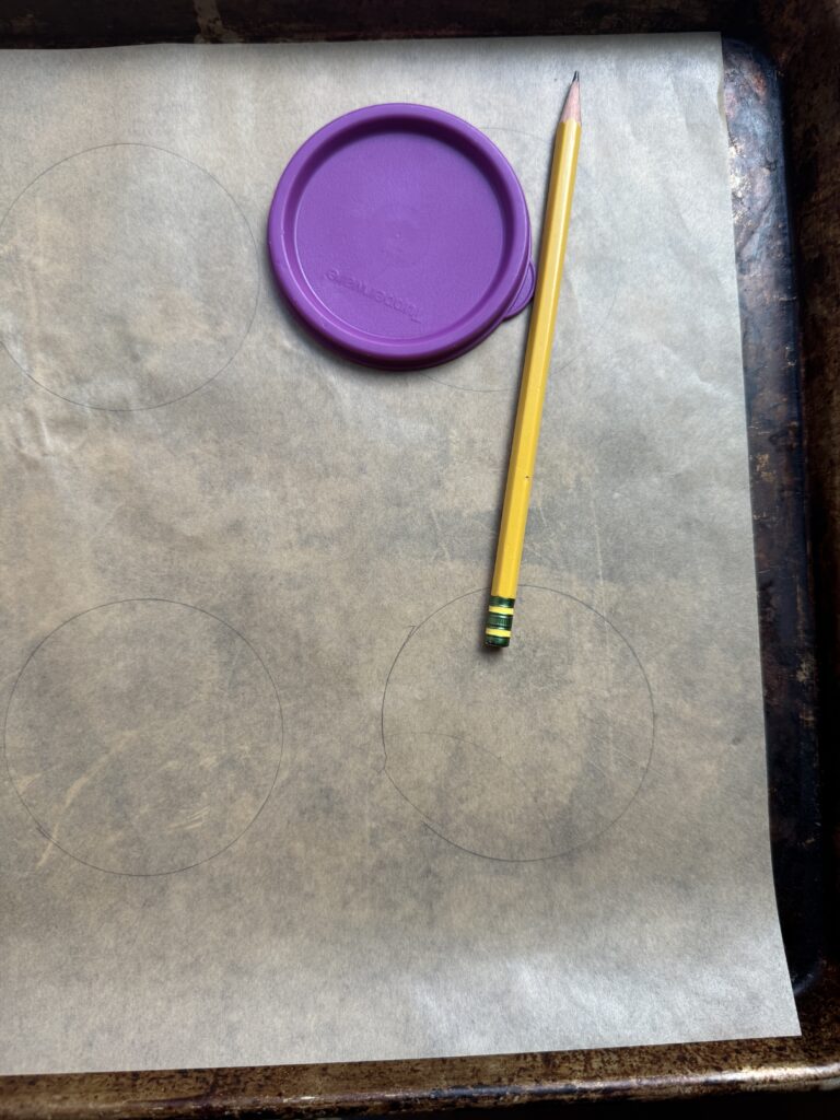 Parchment lined baking sheet, a pencil, and a lid for creating a stencil.