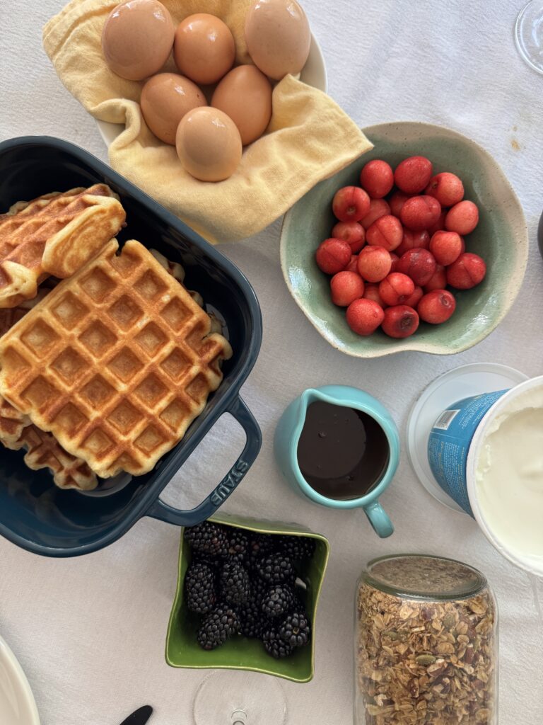 Brunch spread with waffles, jammy eggs, cherries, and granola