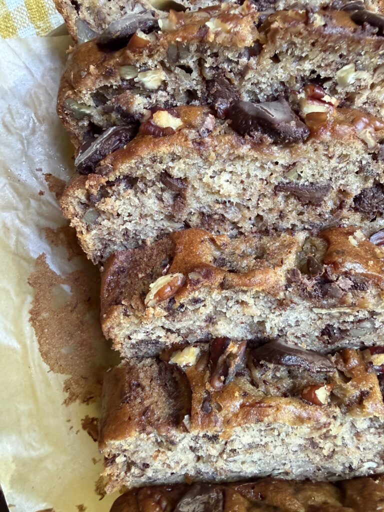 Banana nut bread with chocolate chips sliced on a wooden cutting board