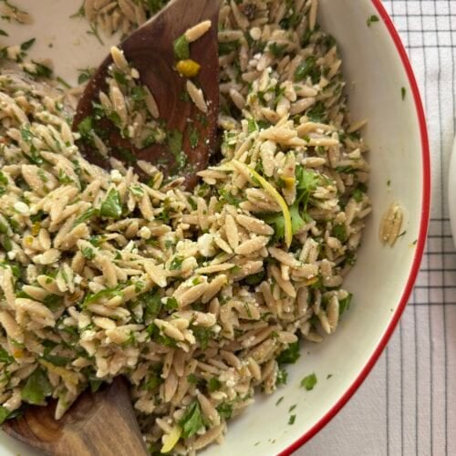 Serving bowl of Lemon Feta Orzo Pasta Salad with serving utensils