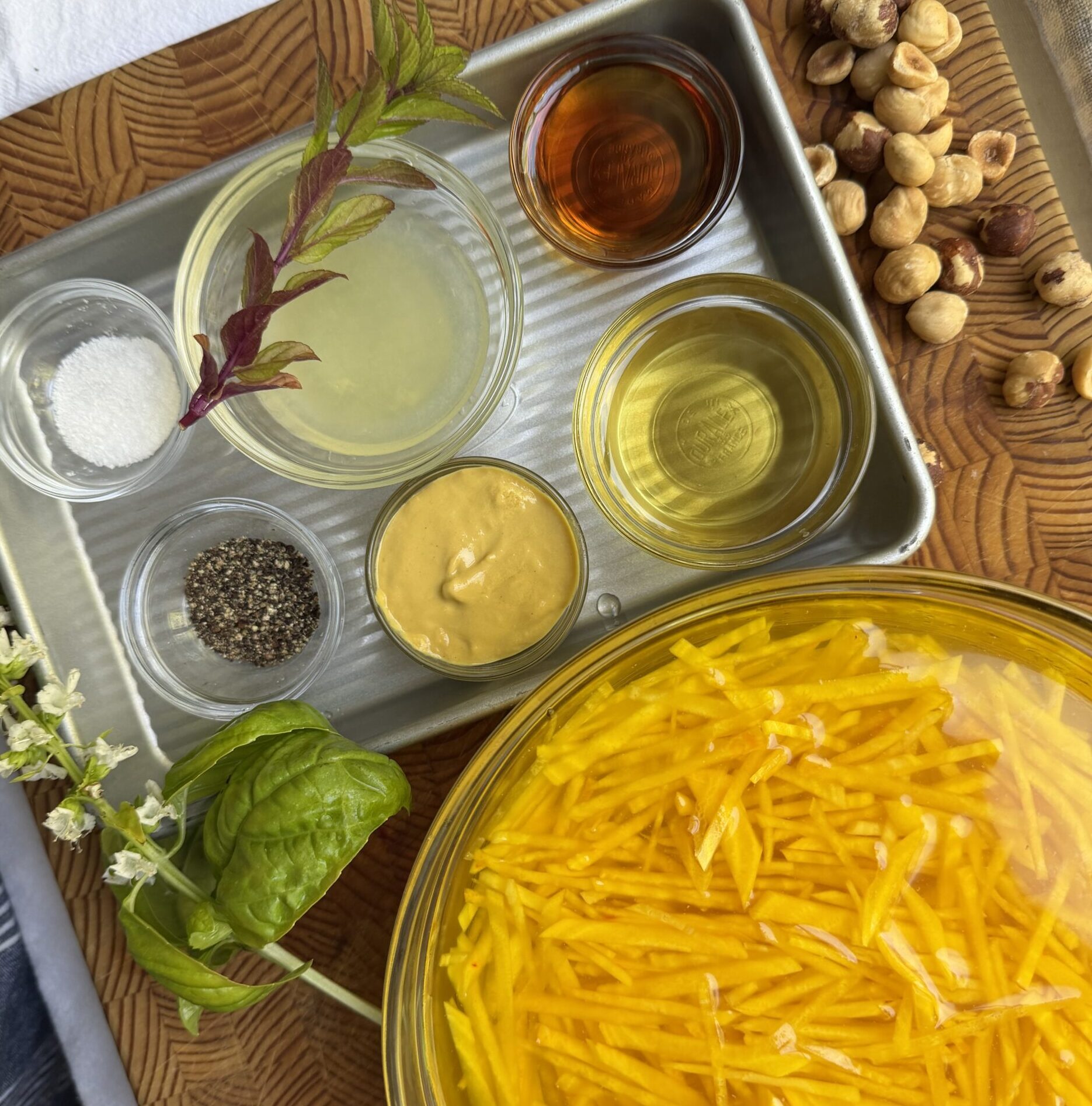 Ingredients for raw golden beet salad including golden beets, olive oil, Dijon mustard, maple syrup, salt, black pepper, herbs