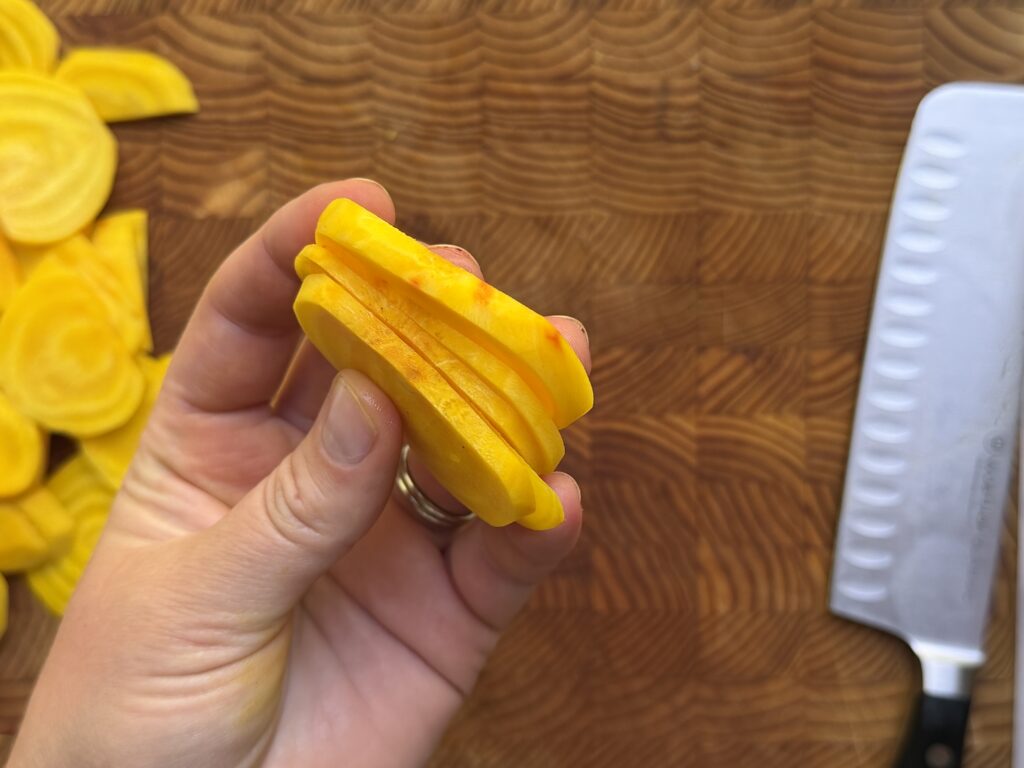 Golden beets sliced and held to show the desired thickness