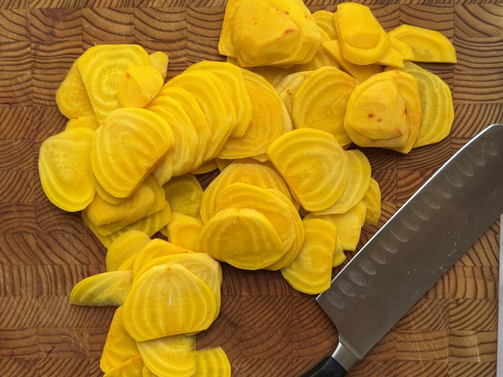 Golden beets sliced into rounds on a wood cutting board