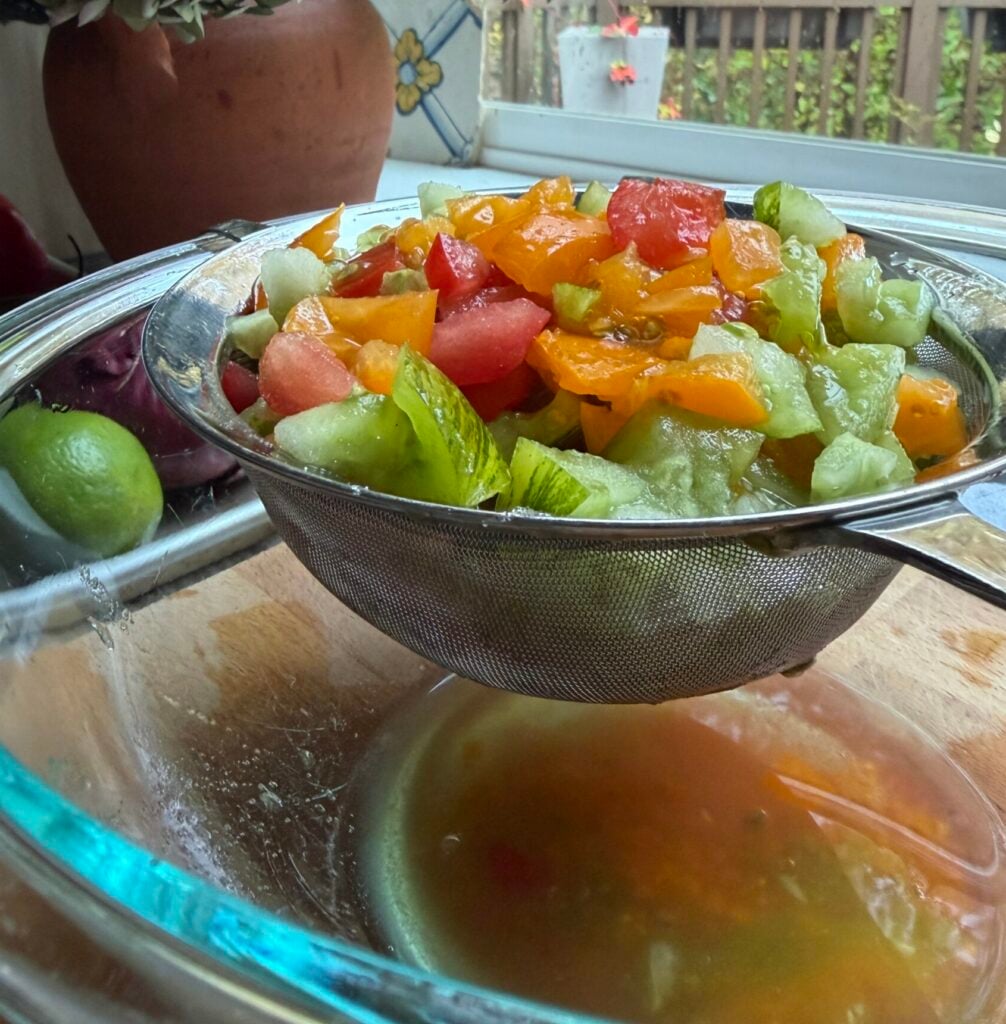 Diced tomatoes in a fine mesh sieve, draining excess liquid.
