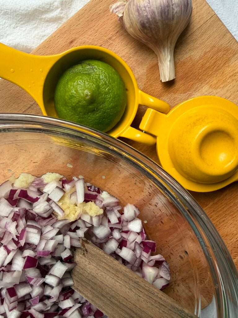 Diced onions and grated garlic soaking in lime juice for black bean and corn salsa.